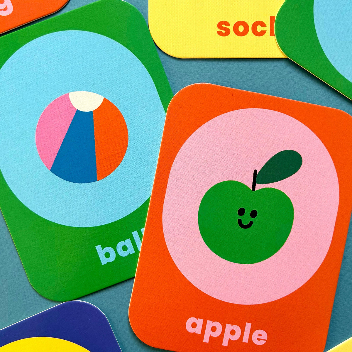 Close-up of ABC Flashcards picture cards showing a colorful ball and a smiling green apple.